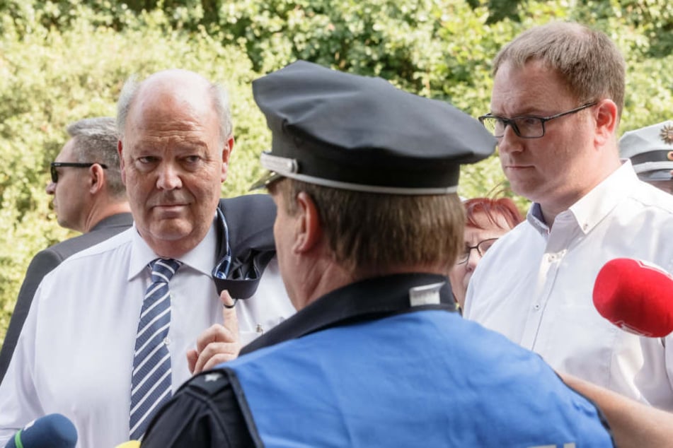 Hans-Joachim Grote (links), Innenminister Schleswig-Holsteins, und Jan Lindenau, Bürgermeister von Lübeck, lassen sich am Tatort von der Polizei informieren.