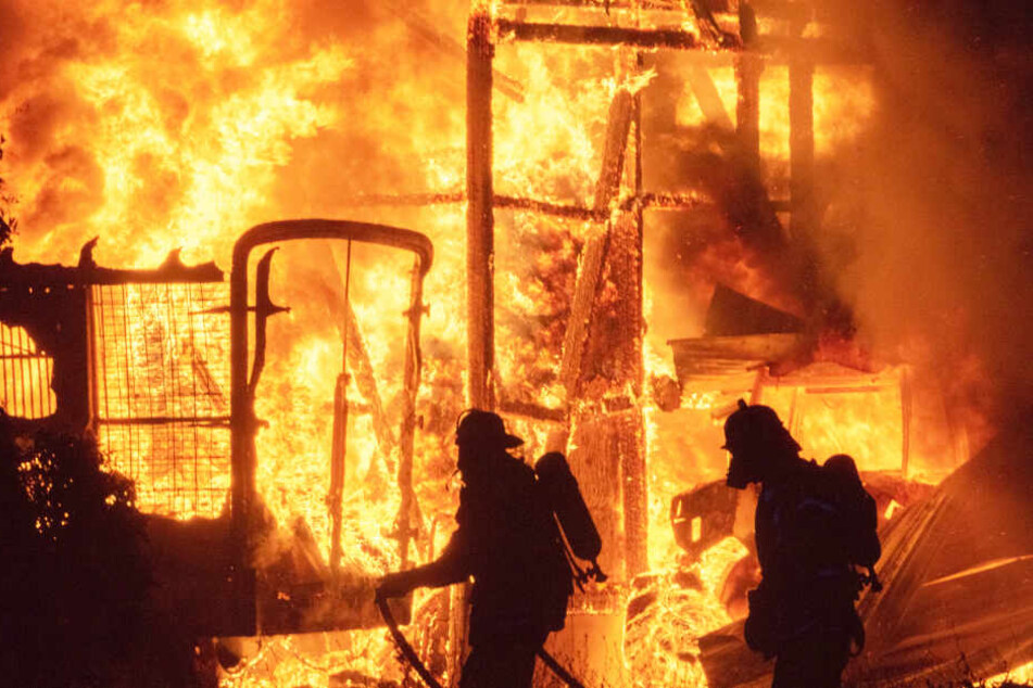 Zwei Feuerwehrleute stehen vor einem Flammenmeer in Tostedt.