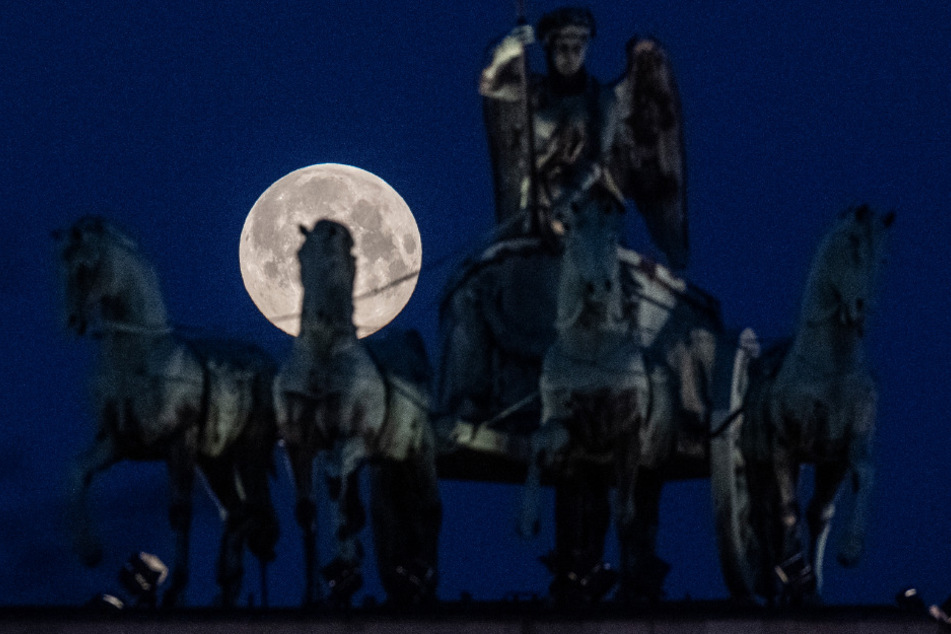 Der Supermond geht hinter dem Brandenburger Tor in Berlin unter.