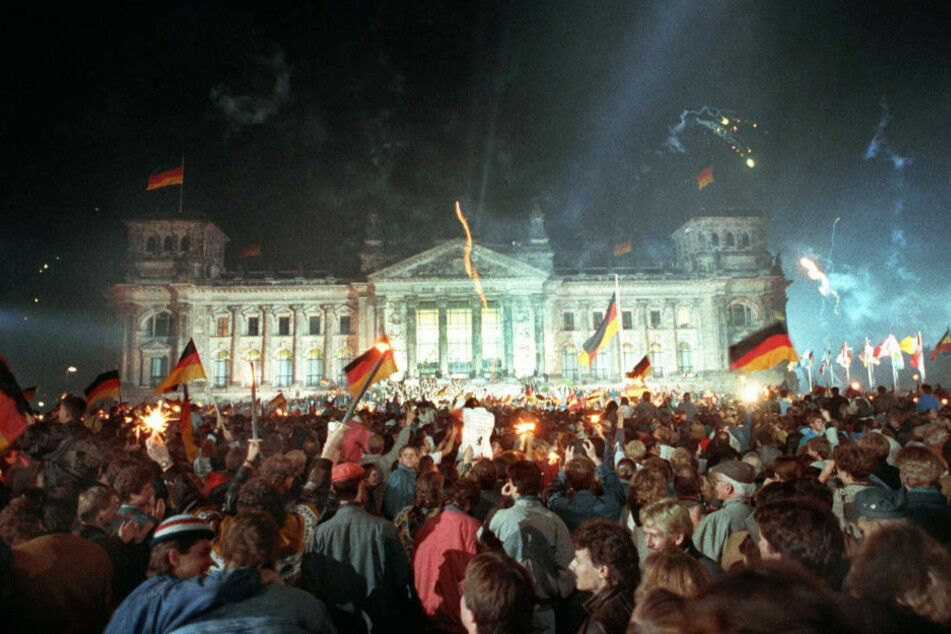 Jubelnde Menschenmassen vor dem Berliner Reichstag, die mit Feuerwerk, Deutschlandfahnen und Volksfesttrubel die wiedergewonnene Einheit Deutschlands am 3. Oktober 1990 feiern. 30 Jahre später beginnt am Samstag in Potsdam die große Einheits-Feier. (Archivfoto)