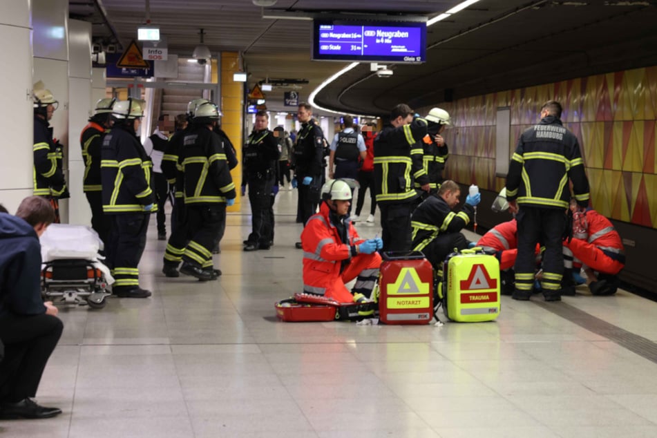 Rettungskräfte behandeln den schwer verletzten 25-Jährigen. Passanten hatten ihn zuvor auf den Bahnsteig gezogen.