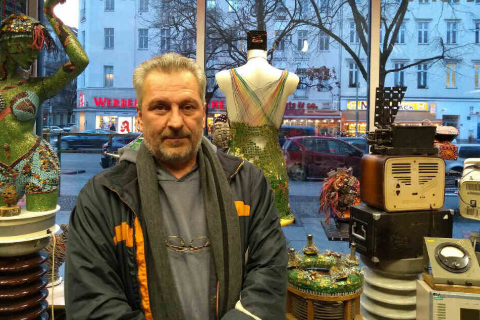 Inhaber Muharrem Batman in seinem Neuköllner Upcycling-Laden neben dem berühmten Elektronik-Kleid.