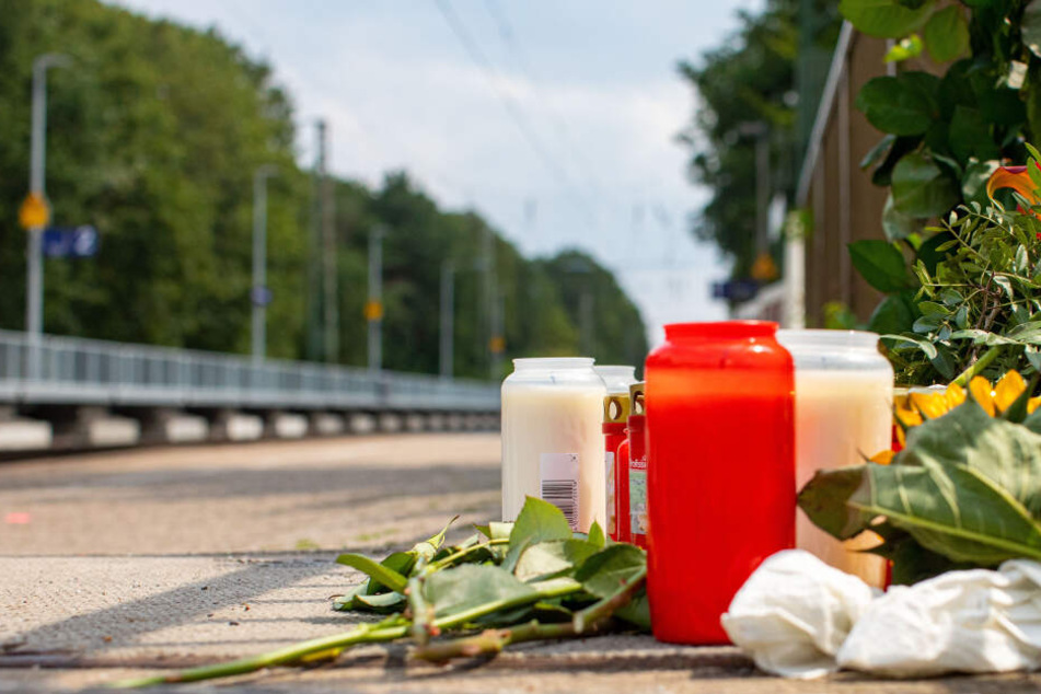 Blumen und Kerzen stehen an den Gleisen am Bahnhof.