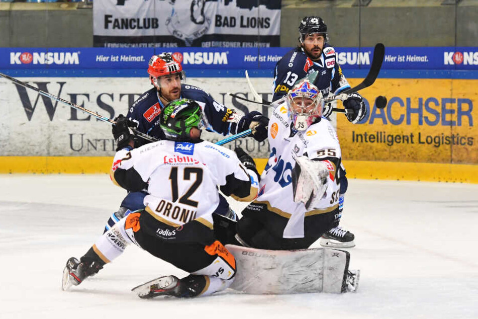 Rot-Helm Nick Huard (#40, Dresden) verzieht gegen Pawel Dronia (#12) und Goalie Olafr Schmidt (beide Ravensburg), ganz hinten: Dale Mitchell (#13, Dresden).