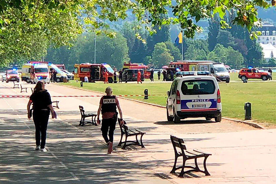 Polizisten und Rettungskräfte gehen nach einem Messerangriff in einem Park zum Tatort.
