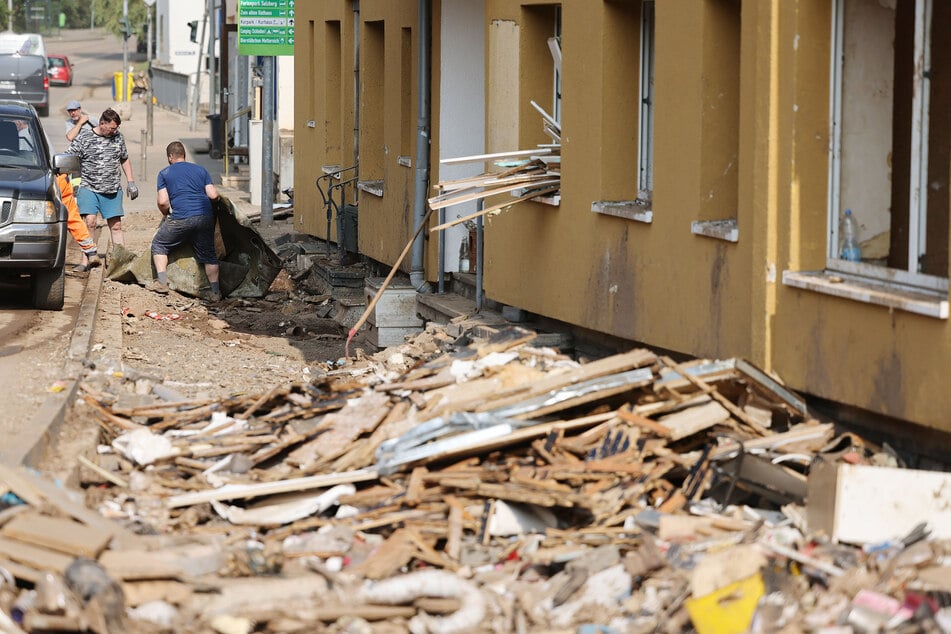 In Gemünd (Eifel) räumten Menschen Ende Juli, zwei Wochen nach der Flut, Schutt und Trümmer aus ihren zerstörten Häusern. Das Hochwasser hatte Milliardenschäden angerichtet, jetzt können Anträge auf Wiederaufbauhilfe gestellt werden.