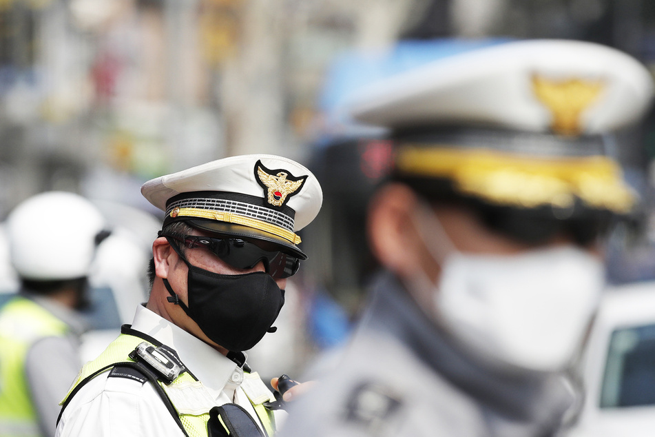 Polizisten mit Schutzmasken stehen Wache.