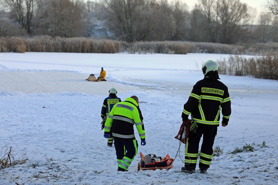 Einsatzkräfte der Feuerwehr betreten vorsichtig die Eisfläche.