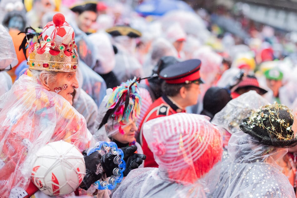 Die Schlangen vor den Kölner Kneipen werden länger. Wer dem Regen auf den Straßen trotzt, schützt sich zumeist mit Regenponchos oder Schirmen.