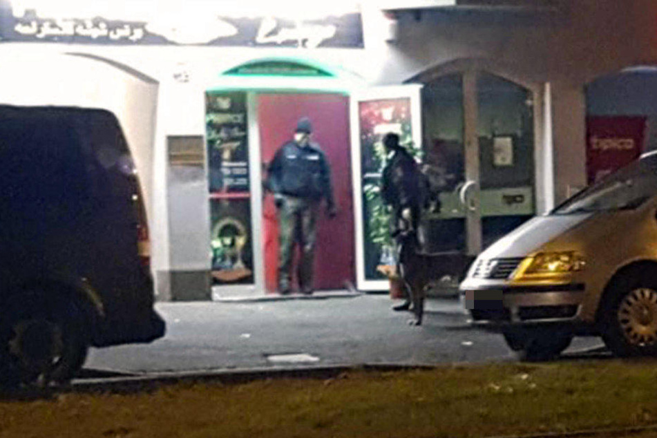 Ein Beamter kommt aus der Shishabar. Davor wartet ein weiterer mit einem Spürhund.