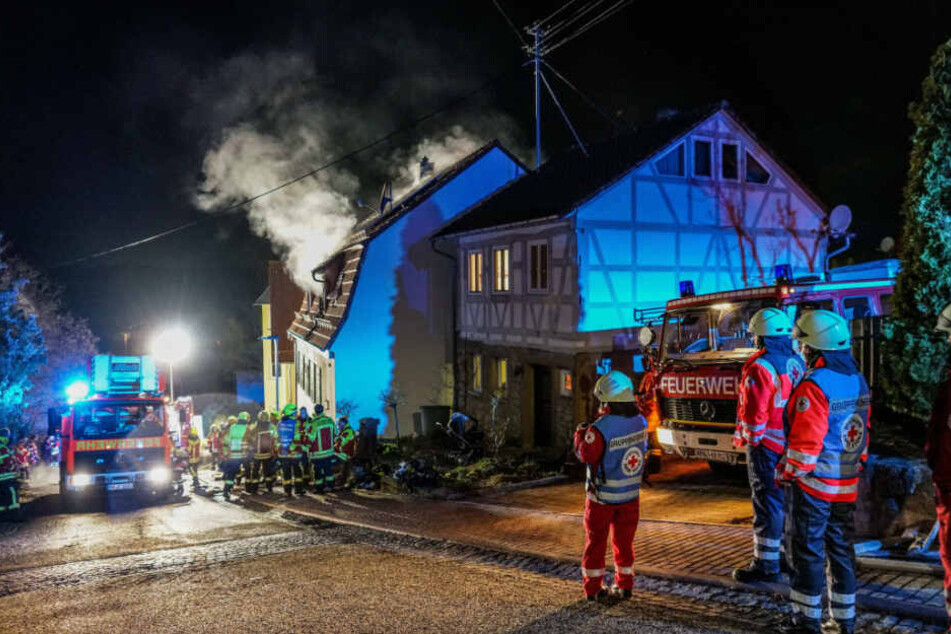 Einsatzkräfte vor dem brennenden Haus.