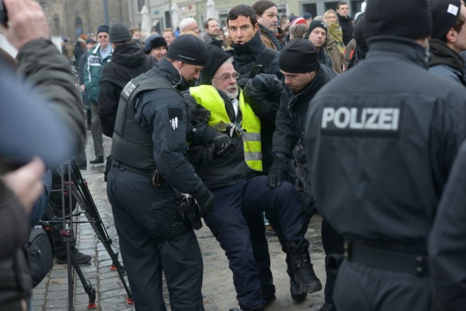 Ein Mann wird von der Polizei weggebracht.