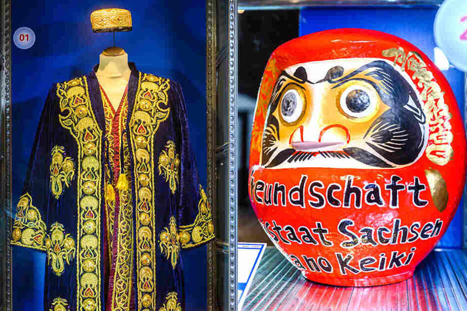 Diese Nationaltracht (l.) aus Samt schenkte Usbekistans Staatspräsident 2001 Kurt Biedenkopf beim Besuch in Dresden. 2007 bekam MP Milbradt diesen Glücksbringer ("Daruma") von einer japanischen Firma (rechts).