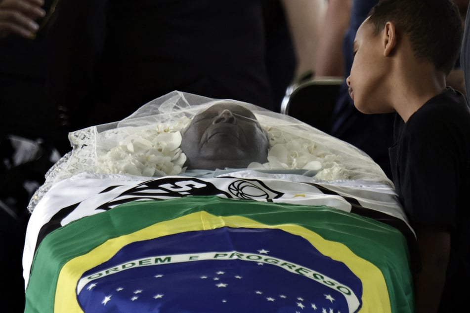 Brazilian soccer legend Pele is seen in his casket on the pitch of his former club Santos' Vila Belmiro stadium as mourners look on.