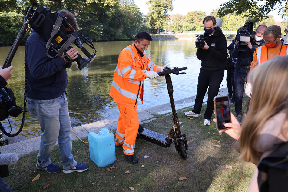 Ein Mitarbeiter der Stadtreinigung schiebt einen E-Scooter, den Taucher der Hamburger Polizei bei der Aktion "Hamburg räumt auf" am Winterhuder Kai aus dem Wasser geborgen haben.