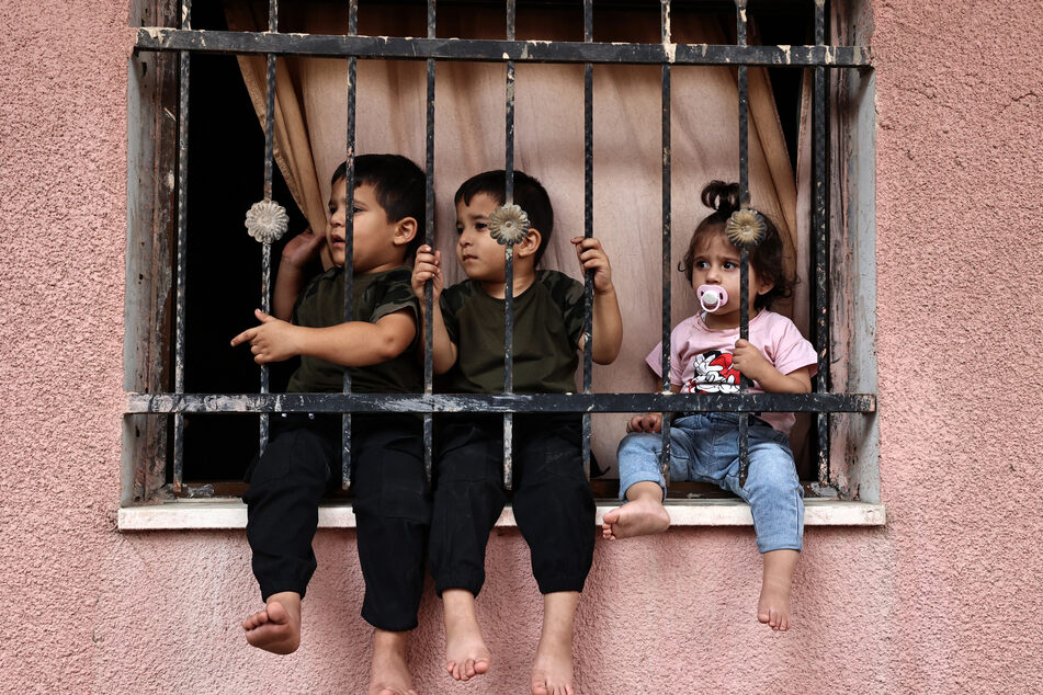 Children watch the funeral procession of a woman killed by Israeli forces in the West Bank. The number of Palestinian children detained in Israeli prisons have nearly quadrupled.