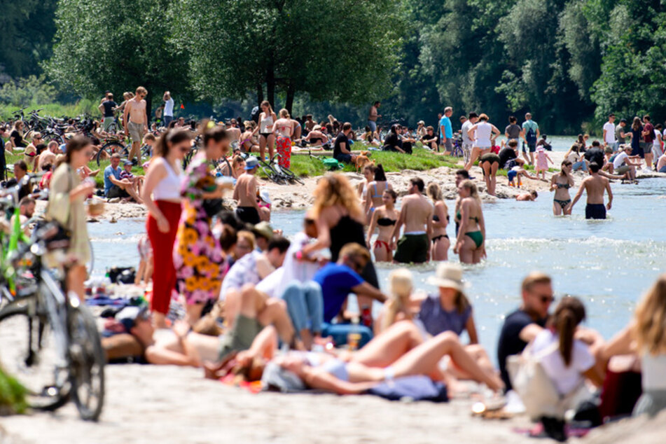 Zahlreiche Menschen genießen das schöne und sonnige Wetter am Ufer der Isar.