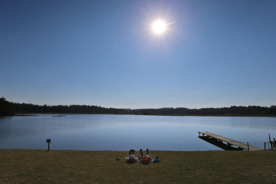Zwei Frauen genießen am Ufer des Elbsees den Sonnenschein.