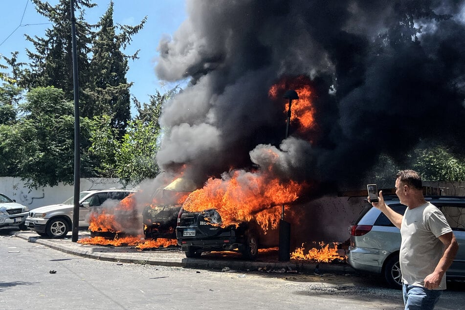 A man takes pictures of burning vehicles following an Israeli airstrike that hit a car in Sidon, Lebanon, on June 10, 2026.