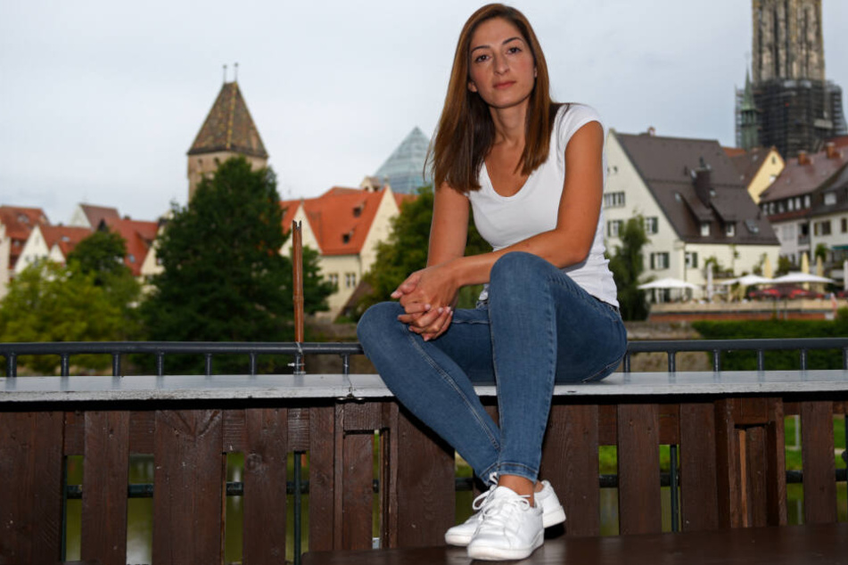 Mesale Tolu sitzt auf einem Geländer vor der Ulmer Altstadt.