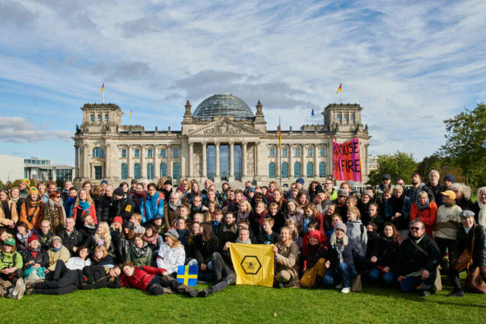 Eine schwedische Gruppe der Klimaschutzbewegung Extinction Rebellion platziert sich auf der Wiese vor dem Reichstag.
