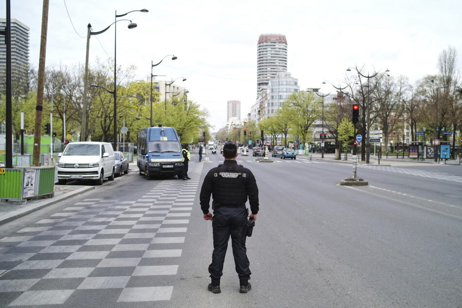 Ein Polizeibeamter patrouilliert an einem Straßen-Kontrollpunkt, um sicherzustellen, dass Personen ohne Sondergenehmigung den Kontrollpunkt nicht passieren. In Frankreich gelten landesweit strenge Ausgangs- und Transportbeschränkungen.