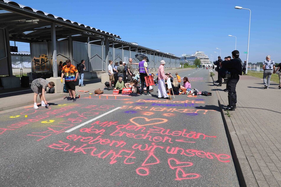 Die 50 Aktivisten – darunter auch fünf Kinder, wie die Polizei gegenüber TAG24 mitteilte – sprühten unter anderem Forderungen wie "Auf dem Pooldeck in die Katastrophe" auf die Zufahrtsstraße.