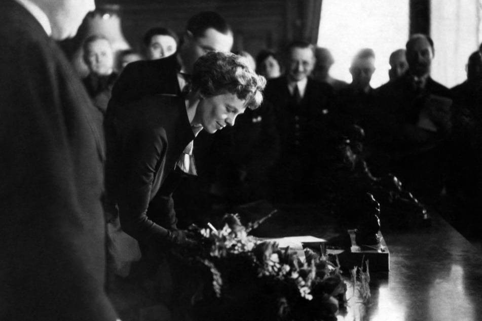 Amelia Earhart signs the guest book during a reception in her honor at the headquarters of the newspaper L'Intran on June 3, 1932, during her visit to Paris after her Transatlantic Solo Flight.