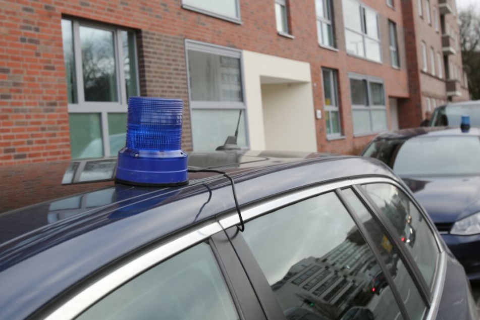 Polizeifahrzeuge stehen während einer Durchsuchung vor einem Mehrfamilienhaus in Hamburg.