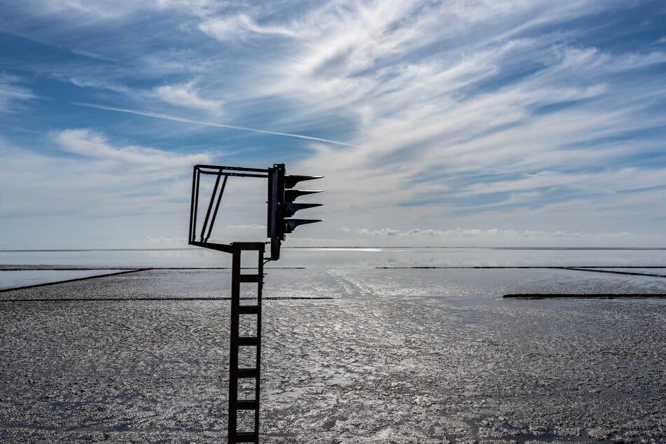 Wolken ziehen vor einem blauen Himmel über das Wattenmeer am Syltdamm vor der Insel Sylt.