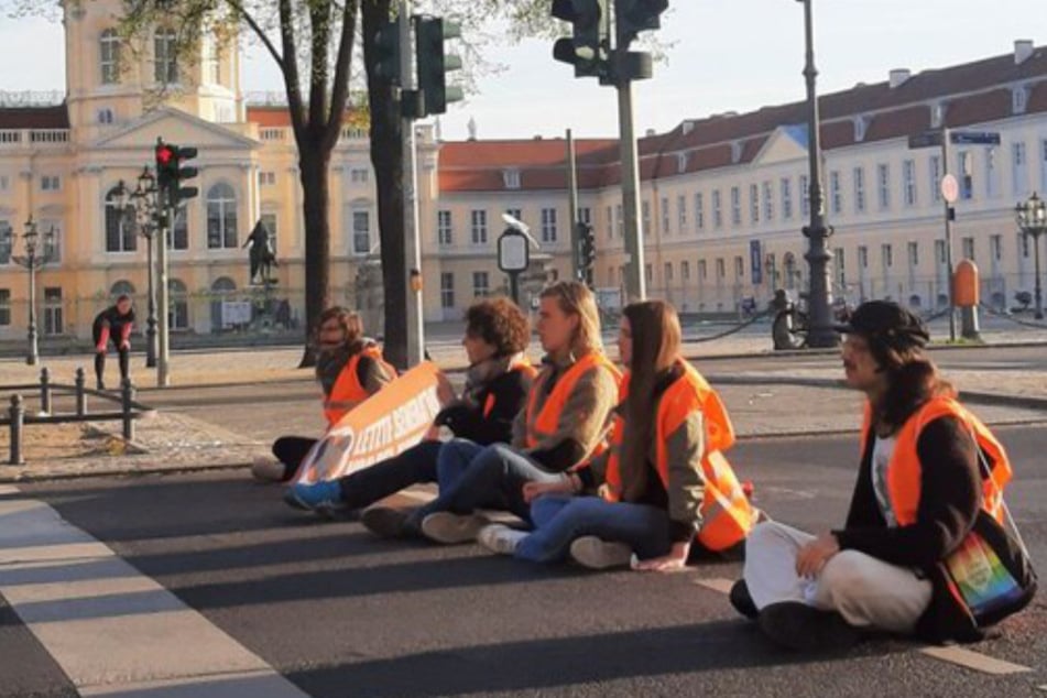 Aktivisten der "Letzten Generation" sitzen auf der Straße und blockieren den Verkehr in Berlin.