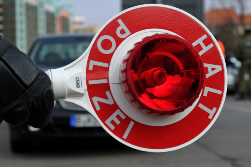Ein Polizist hält eine Polizeikelle in der Hand. (Symbolbild)