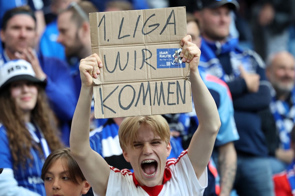 Ein junger HSV-Fan hält ein Schild mit der Aufschrift "1. Liga wir kommen" hoch. Die Überzeugung im Volkspark ist riesig.