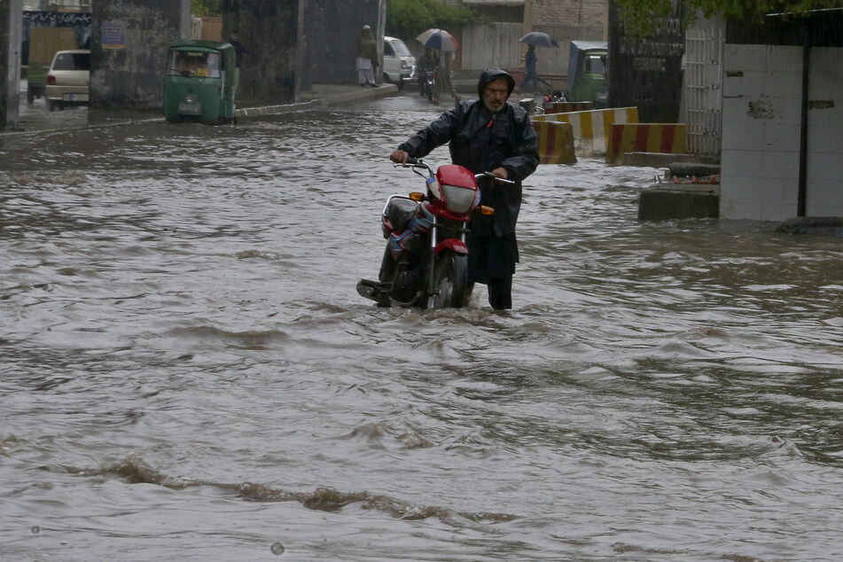 Ein Pakistaner watet nach starken Regenfällen durch den überfluteten Ort Peschawar.