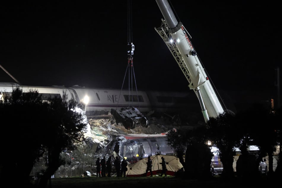 Kräne hoben in der Nacht auf Donnerstag zwei besonders beschädigte Waggons an, um nach weiteren möglichen Opfern suchen zu können.