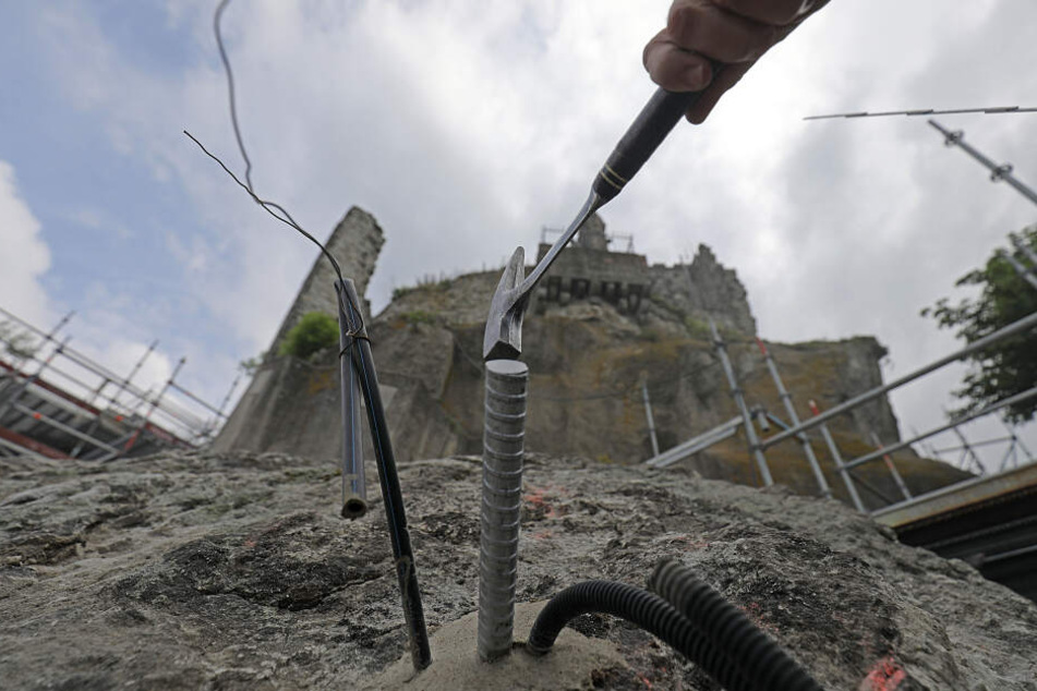 Arbeiter setzen unterhalb der Burgruine Anker, um einen Felssturz zu vermeiden.