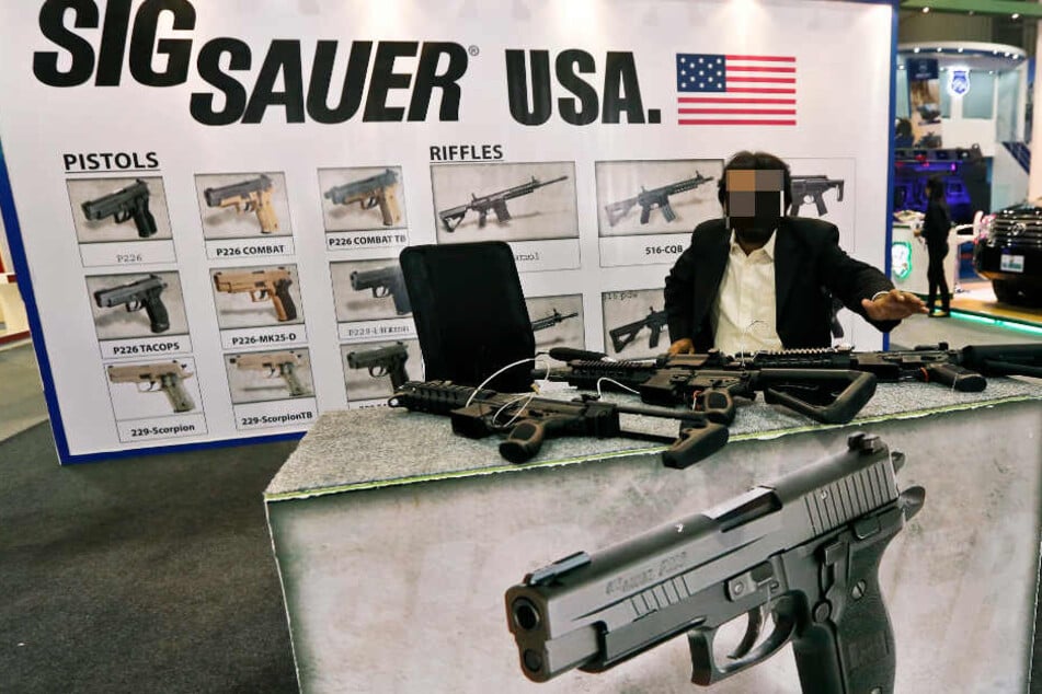 Ein Mann präsentiert auf einer Messe Waffen von Sig Sauer.