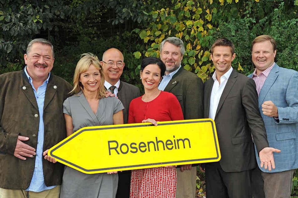 Darsteller der "Rosenheim Cops" vor dem entsprechenden Ortsschild.