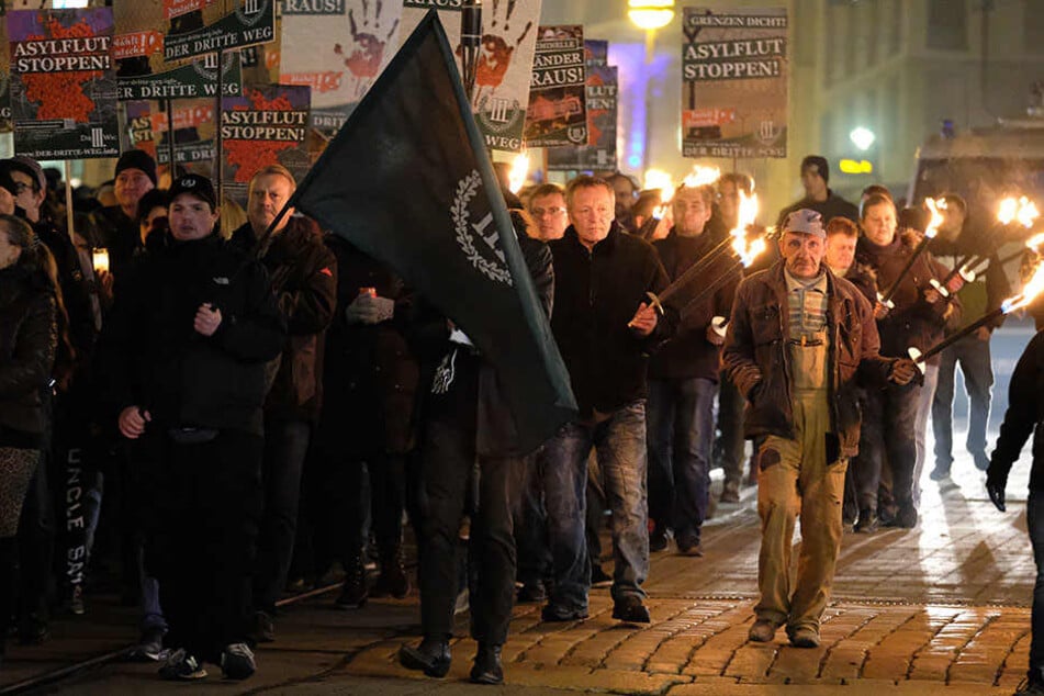 Teilnehmer einer rechten Demonstration versammeln sich mit Transparenten und Fackeln in der Innenstadt.