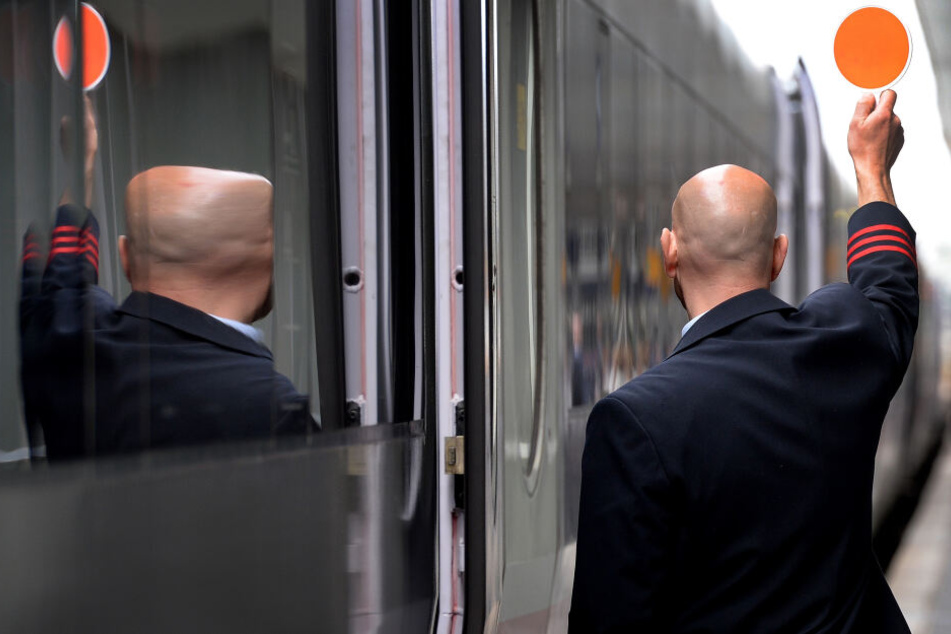Ein Schaffner signalisiert dem Lokführer die Abfahrt.