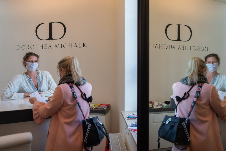 Die Dresdner Modedesignerin Dorothea Michalk (l.) verkauft einer Kundin einen Mundschutz.
