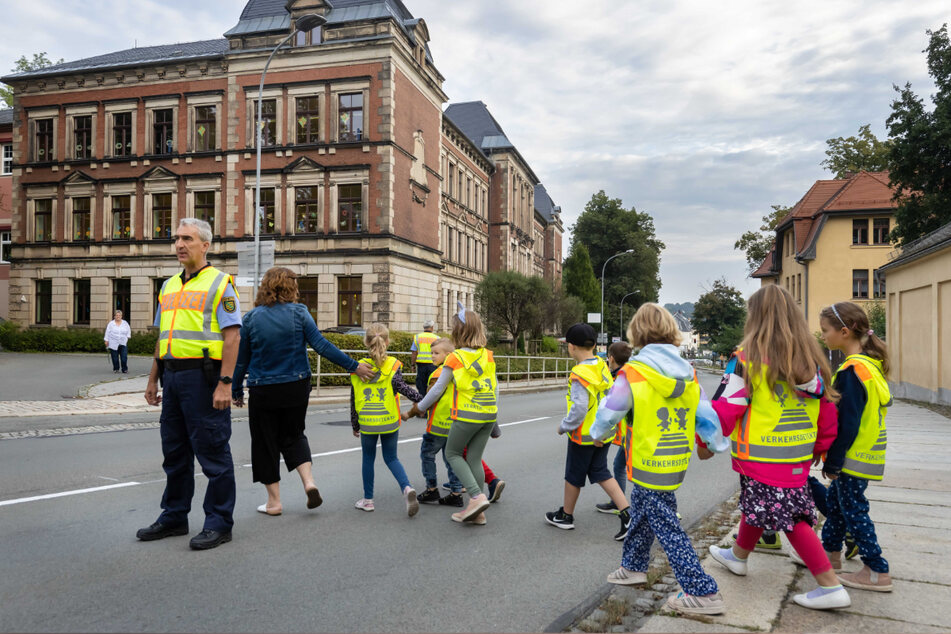 Polizeihauptmeister Uwe Huster (60, l.) sorgt dafür, dass die Erstklässler an der Schule gefahrlos die Hauptstraße überqueren können.