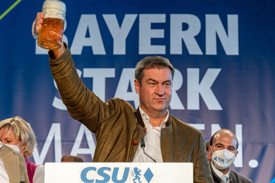Bayerns Ministerpräsident Markus Söder (CSU) steht beim Politischen Frühschoppen Gillamoos mit einer Maß Bier auf der Bühne.