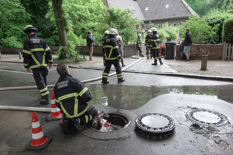 Feuerwehrleute pumpen Wasser aus der Einfahrt und dem Keller eines Hauses.