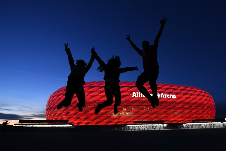 Drei Fans springen nach der Partie in der Fußball Bundesliga FC Bayern München - Borussia Mönchengladbach vor der Allianz Arena in die Höhe.