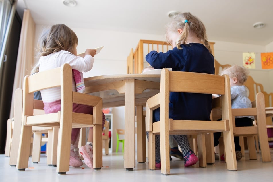 Die Kinder einer Kindergrippe sitzen im Rahmen der Notbetreuung während des Mittagessens an einem Tisch.