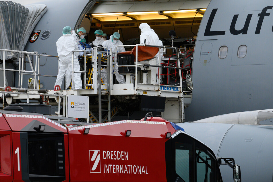 Medizinisches Personal kümmert sich am Dresdener Flughafen um einen Corona-Patienten, der mit der Luftwaffe nach Köln geflogen wird.
