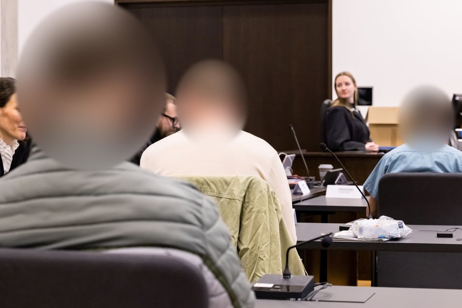 Drei angeklagte Männer sitzen im Sitzungssaal des Strafjustizzentrums im Landgericht Nürnberg-Fürth.