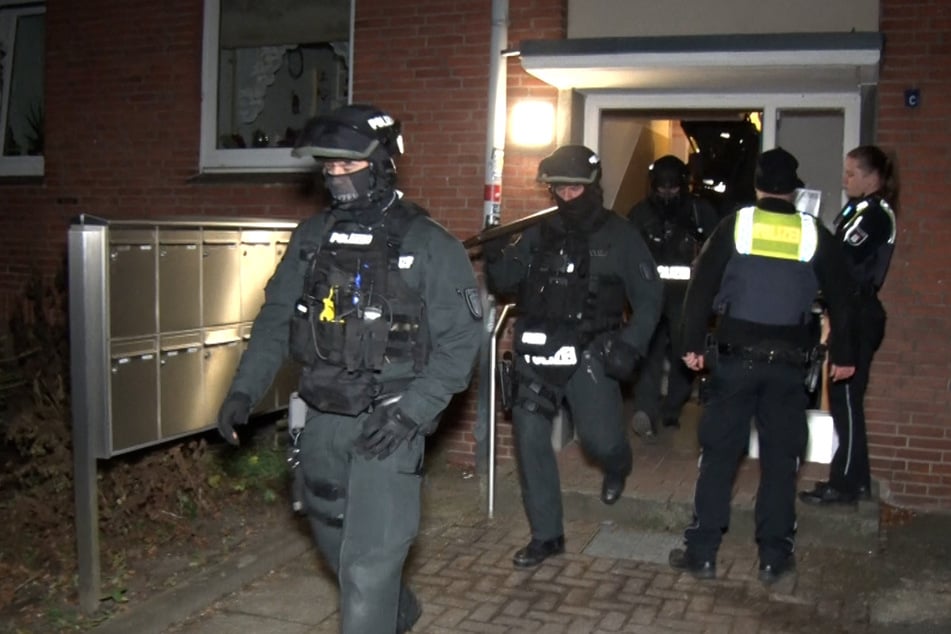 Schwer bewaffnete Einsatzkräfte verlassen ein Mehrfamilienhaus in Hamburg-Wilhelmsburg.