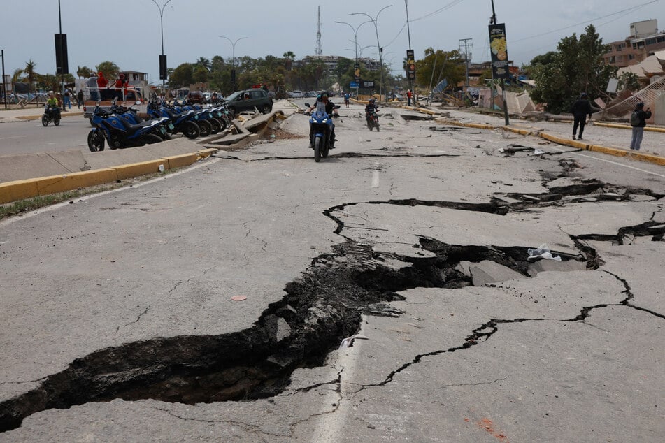 Motorradfahrer fahren auf einer Straße, die durch die Erdbeben, die La Guaira in Venezuela einen Tag zuvor erschüttert hatten, aufgerissen wurde.